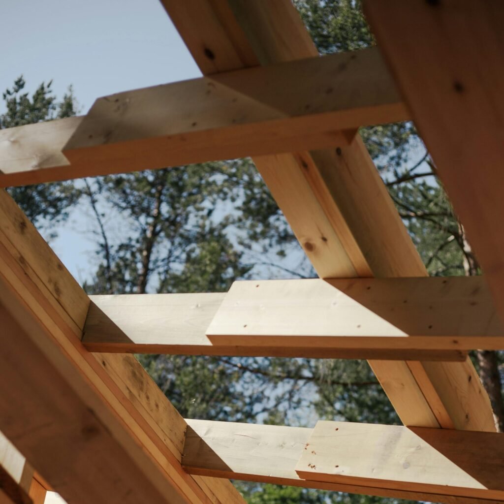 Close-up view of wooden beams forming a house roof structure against a sky background.
